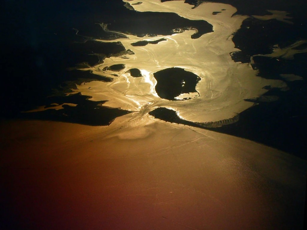 Poole Habour in Dorset, England, as seen at sunset from a plane. Looking west-northwest into the harbour. The three islands visible just inside the entrance are (from left to right): Green Island, Furzey Island, and Brownsea Island.