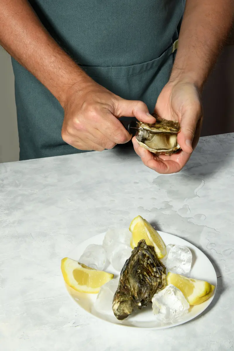 Knife sliding along the inside of the oyster shell to cut the adductor muscle cleanly