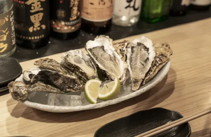 wakayama oysters on a plate of ice shucked and served with lemon.